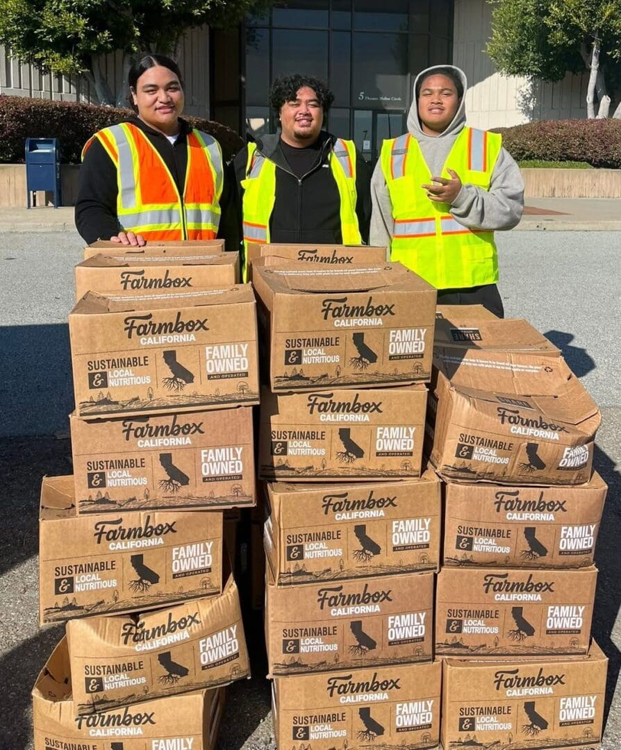 Three people standing behind stacked boxes labeled 'Face Masks'.